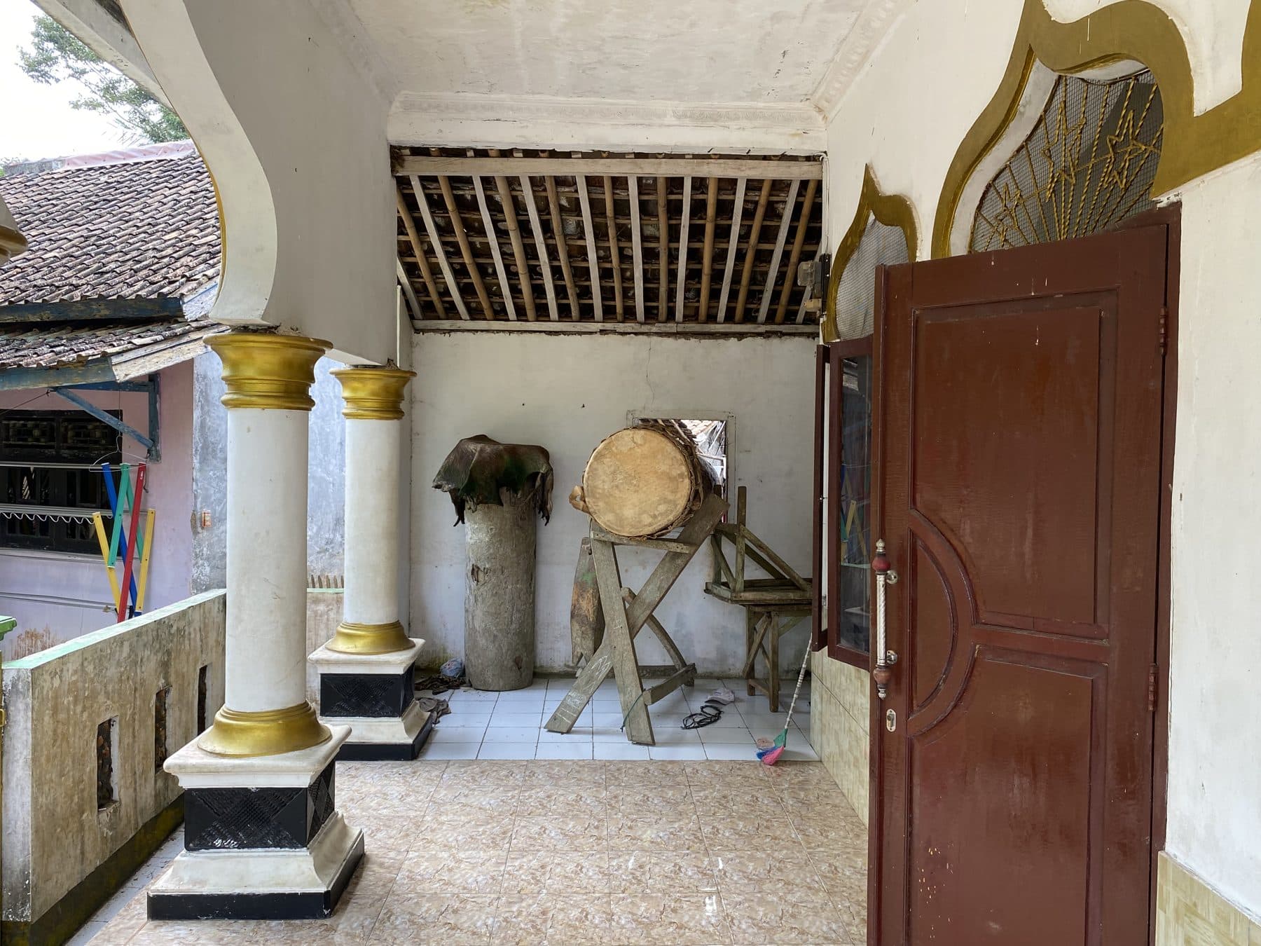 Bagian dalam masjid dengan tiang kayu keemasan dan bedug di Desa Tembong.