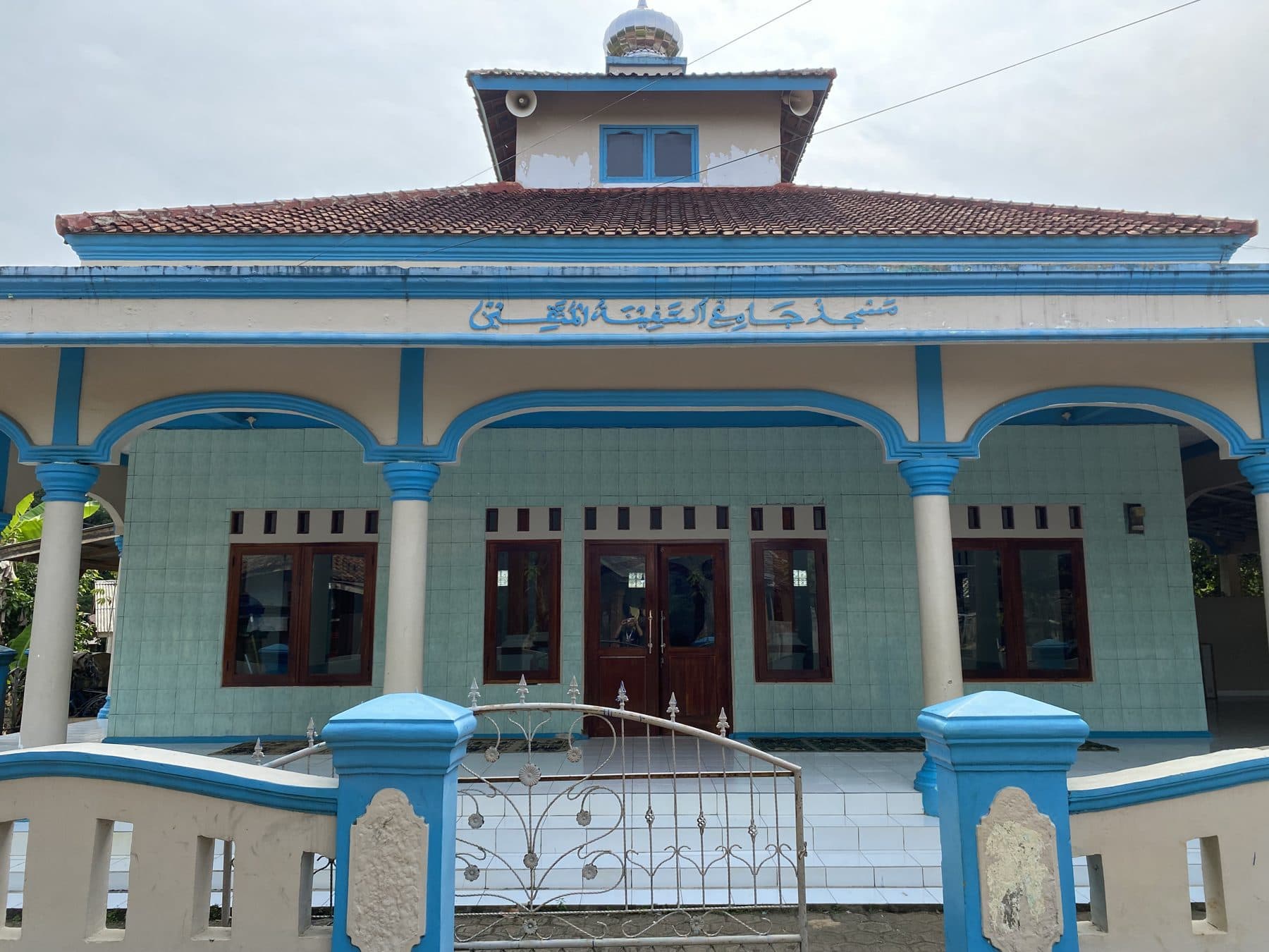 Masjid berkubah dengan dinding biru muda dan pagar di kampung Desa Tembong.