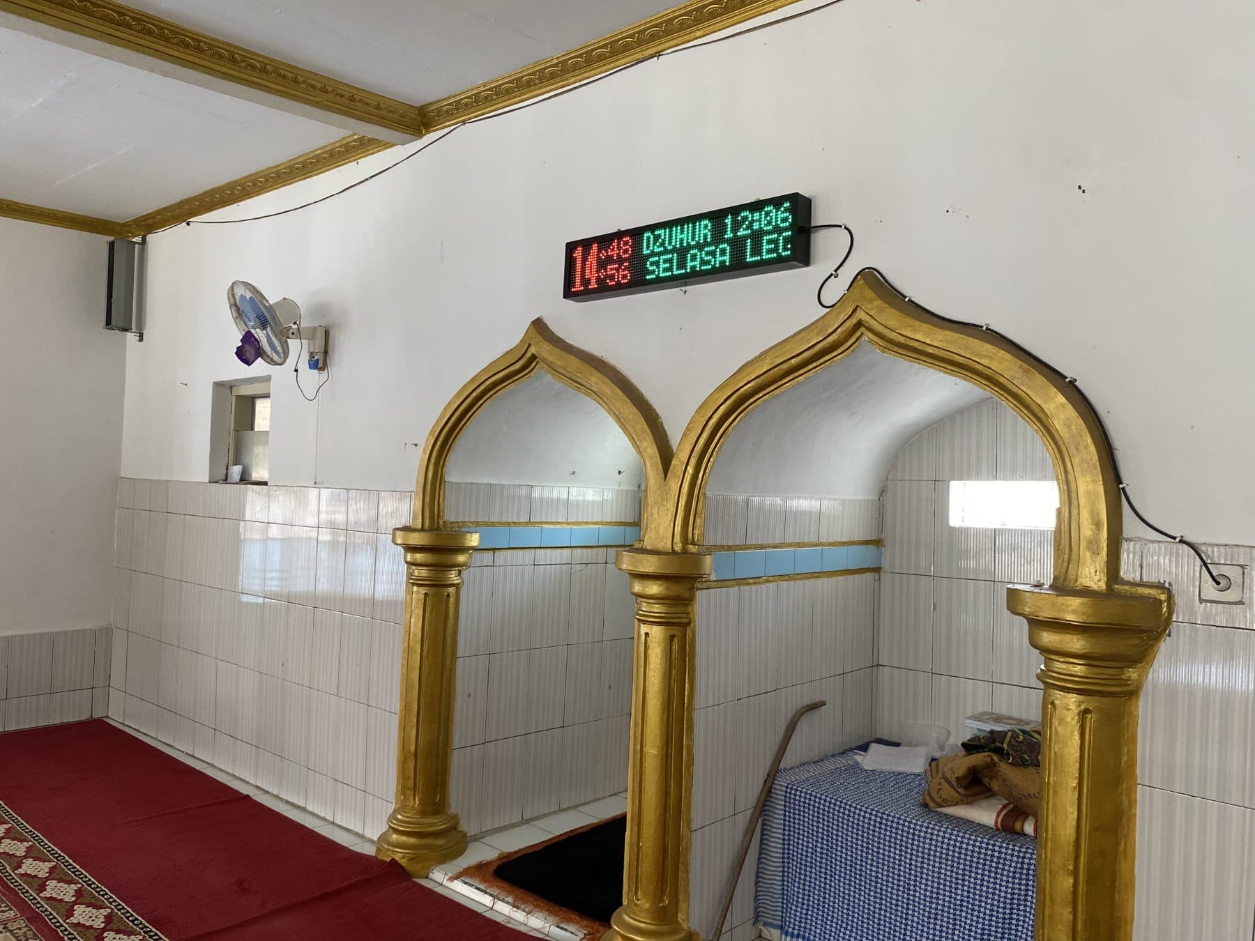 Mihrab berhias lengkung keemasan dengan karpet merah di sebuah masjid Desa Tembong.