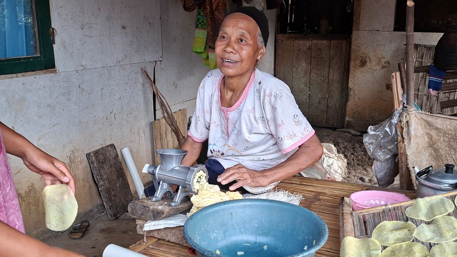 Pengrajin menggiling singkong kukus menjadi adonan opak.