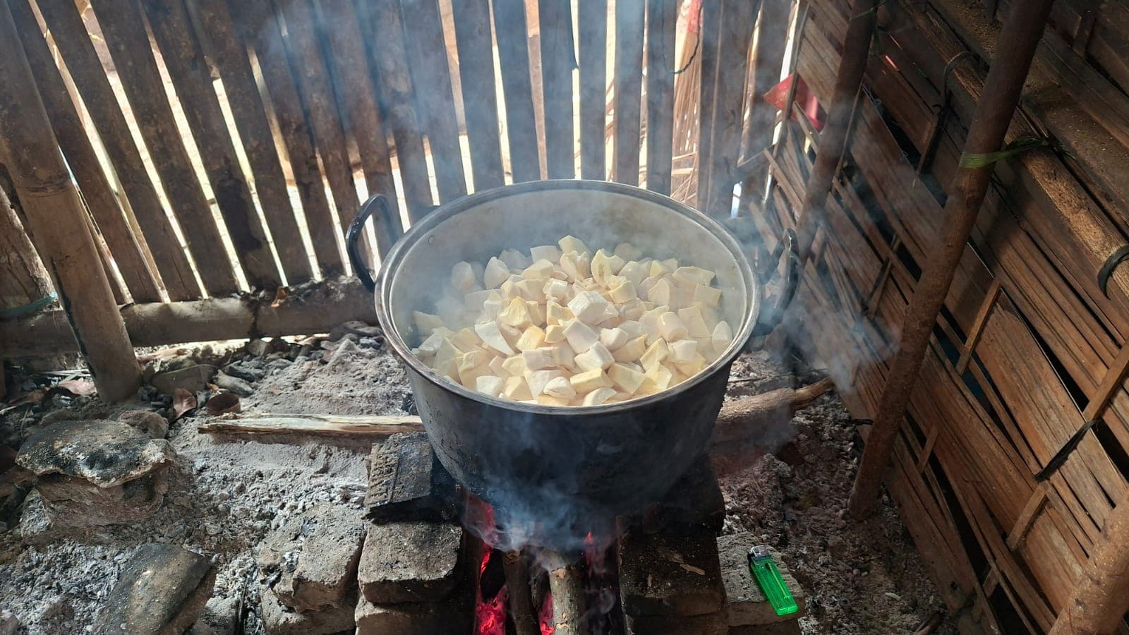 Potongan singkong dikukus dalam panci besar di atas tungku.