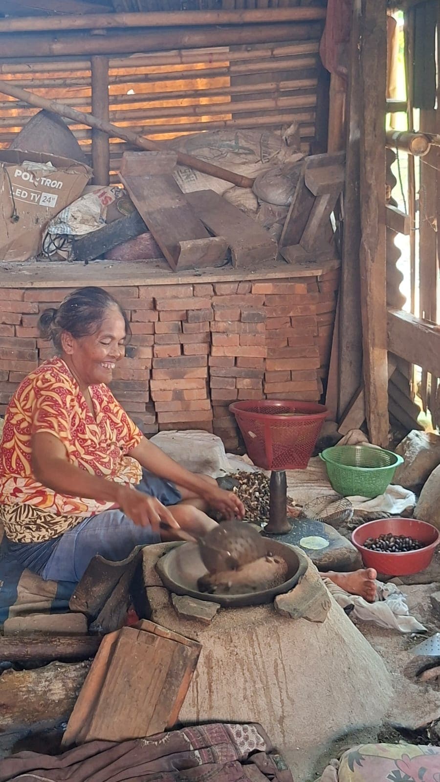 Warga menyangrai biji melinjo dalam kuali tanah di atas tungku kayu.