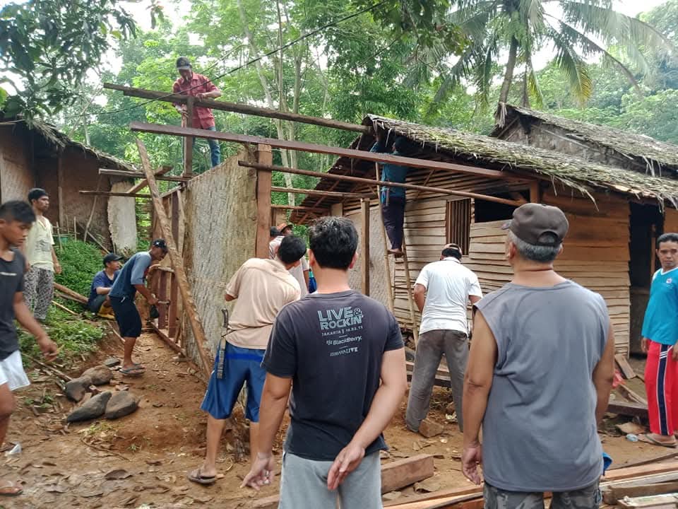 Warga bergotong royong memperbaiki bangunan berdinding bilik di Desa Tembong.