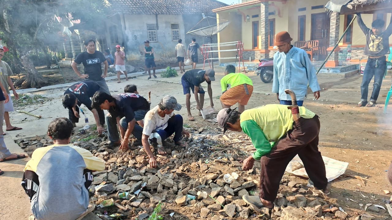 Warga menata batu di jalan kampung Desa Tembong.