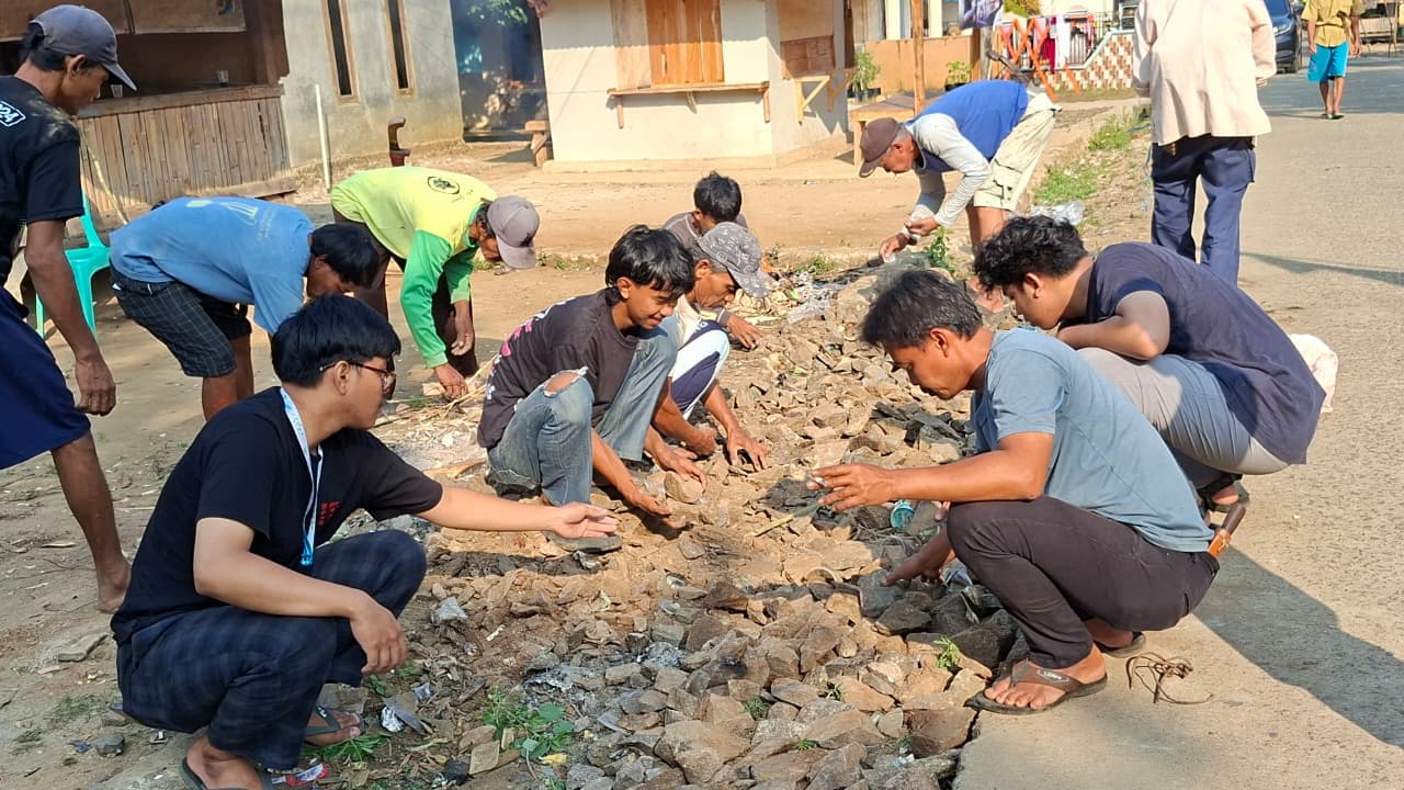 Warga dan anak muda menata batu di jalan kampung Desa Tembong.