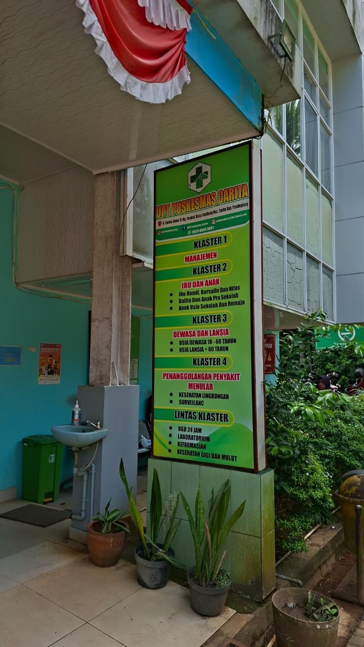 Papan layanan UPT Puskesmas Carita yang memuat daftar klaster pelayanan.